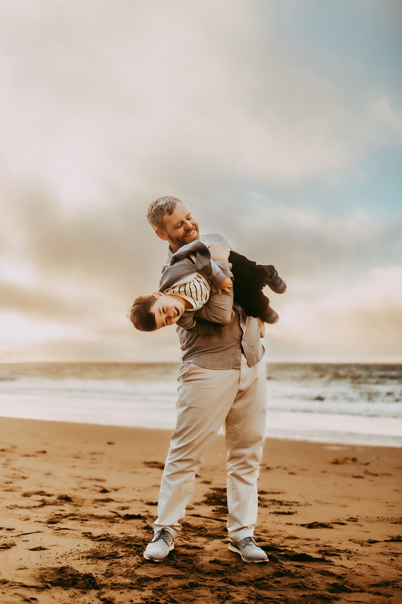 Shefali Parekh | Capturing Joy and Laughter: The Family Session at Baker Beach A man holding his child on the beach at sunset