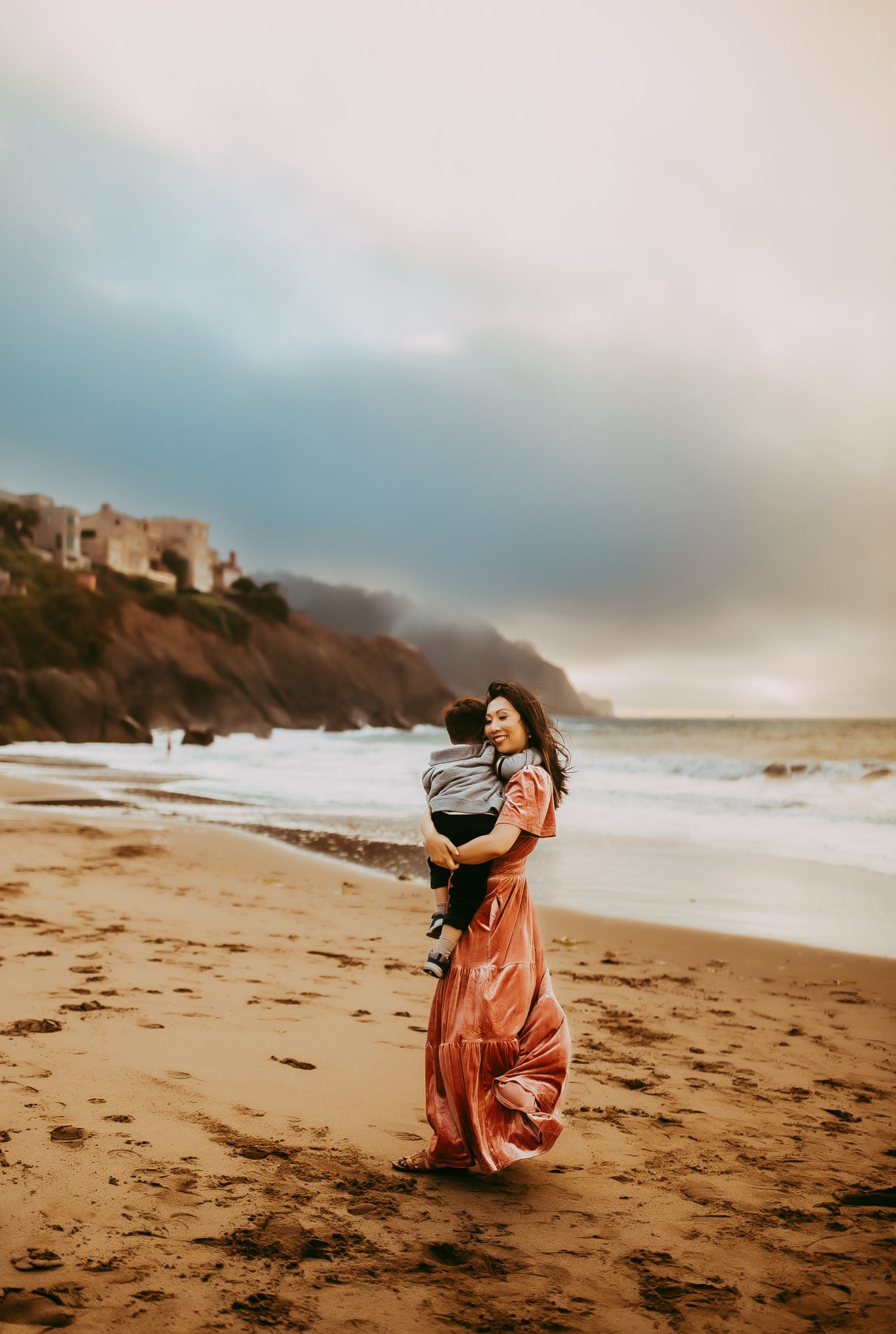 Shefali Parekh | Capturing Joy and Laughter: The Family Session at Baker Beach A mother holding her son on a beach