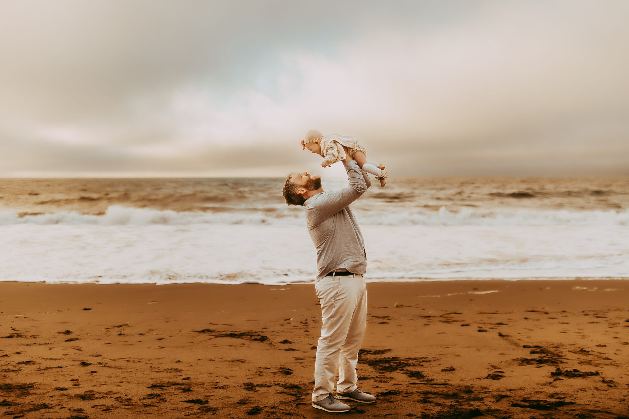Shefali Parekh | Capturing Joy and Laughter: The Family Session at Baker Beach A father lifting his son on a sandy beach