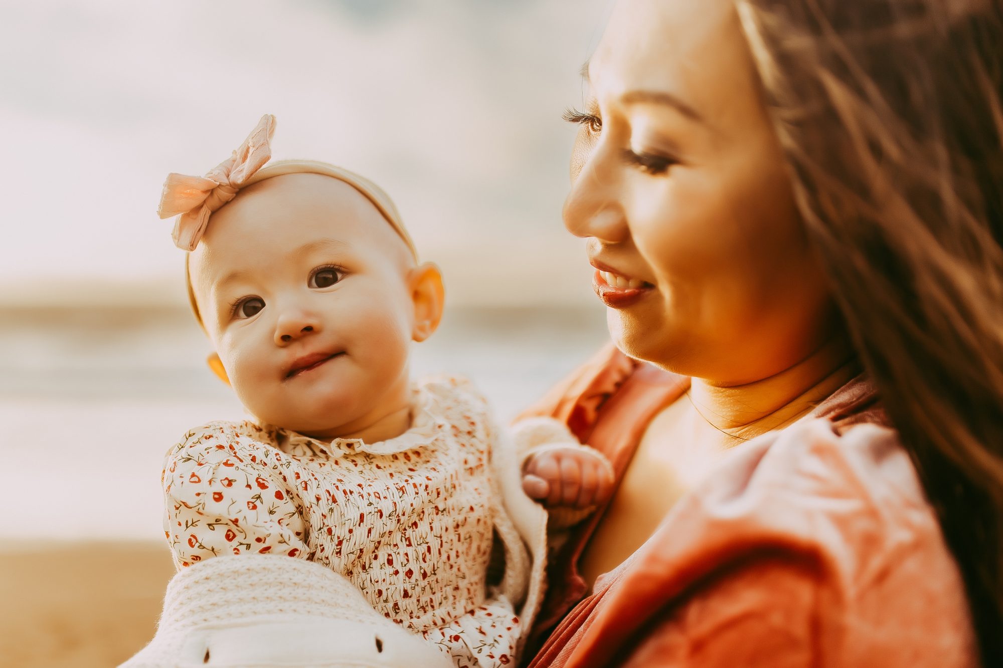 Shefali Parekh | Capturing Joy and Laughter: The Family Session at Baker Beach A woman cradling a baby on a sandy beach