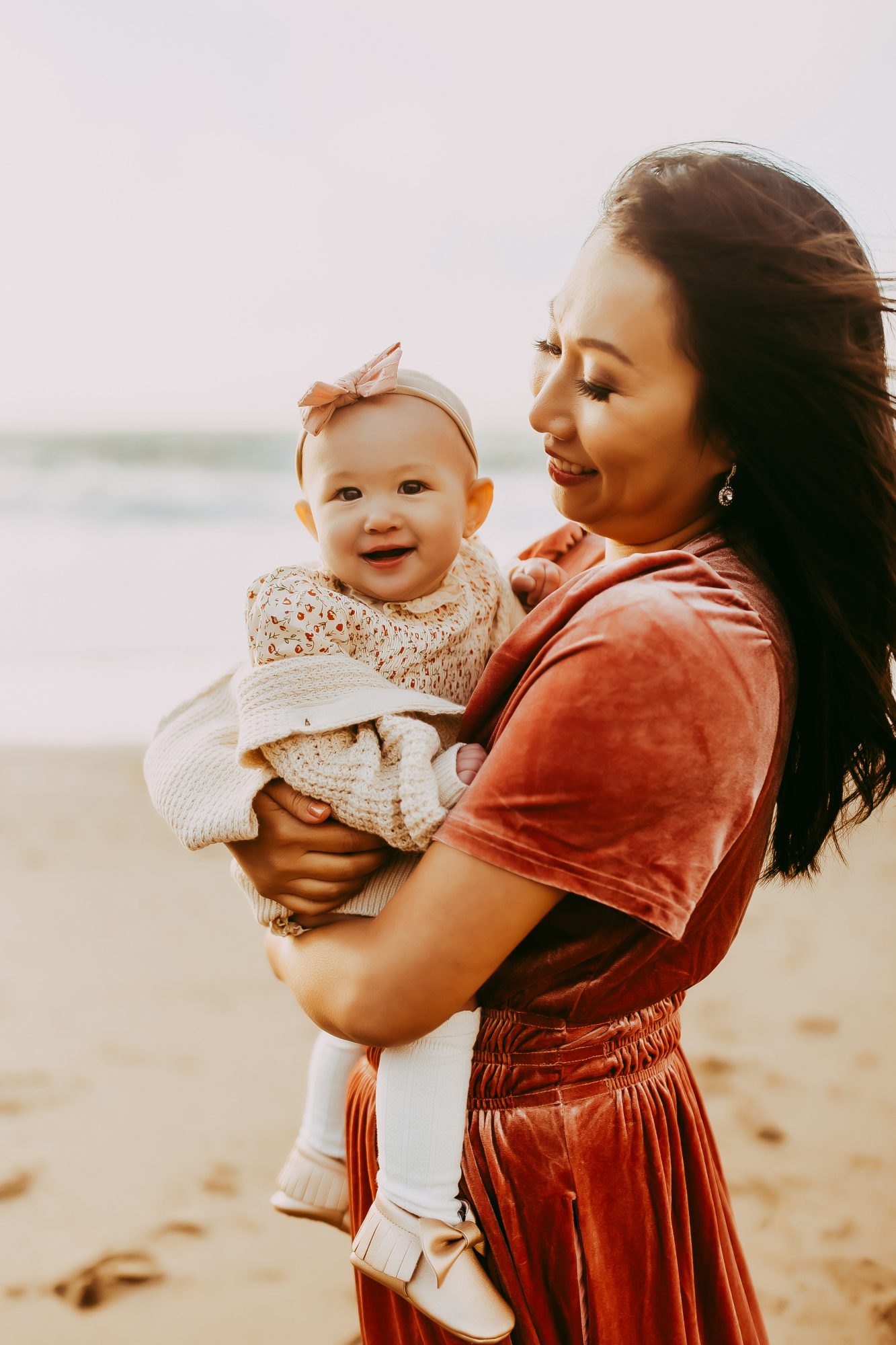 Shefali Parekh | Capturing Joy and Laughter: The Family Session at Baker Beach A mother cradling her infant on a sandy beach