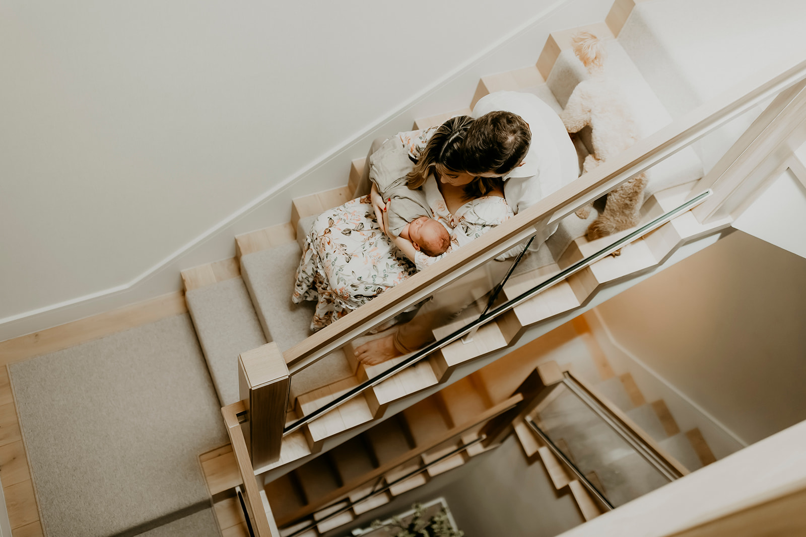 Shefali Parekh | Heartwarming In-Home Newborn Session: Maggie & Alex Black in Cow Hollow, San Francisco Family sitting on stairs with baby in the mother's lap