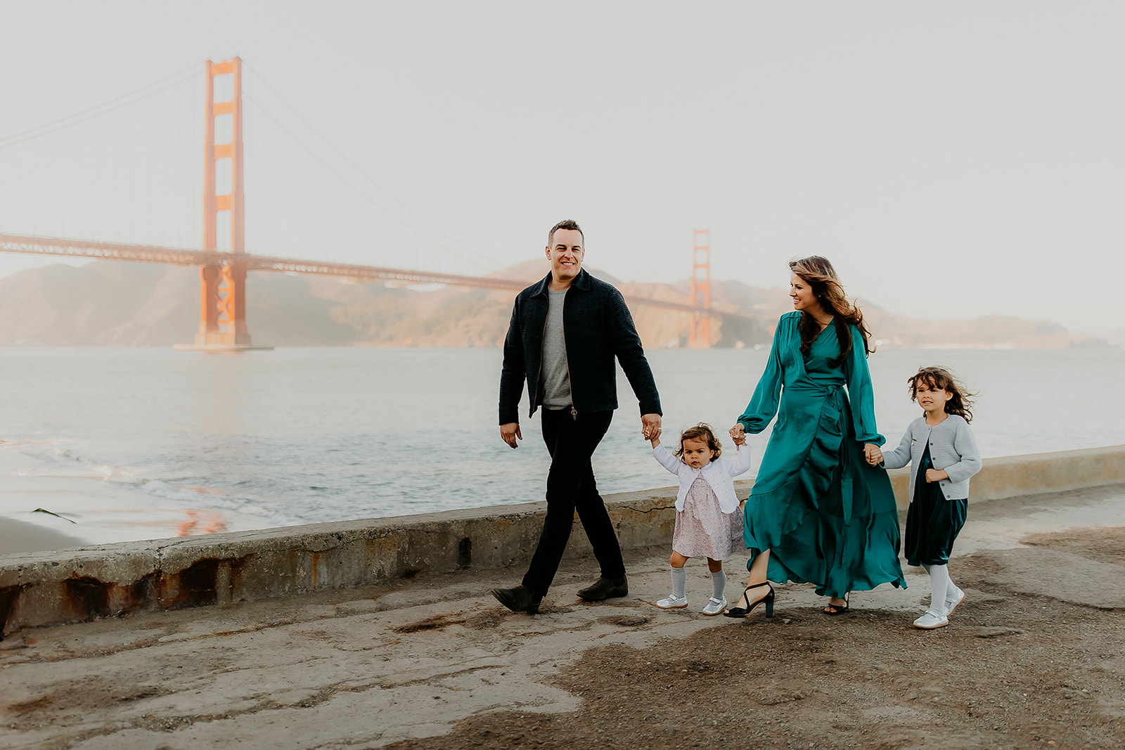 Shefali Parekh | The Best Location for Family Photography: Crissy Field Family walking by the seaside with golden gate bridge in background