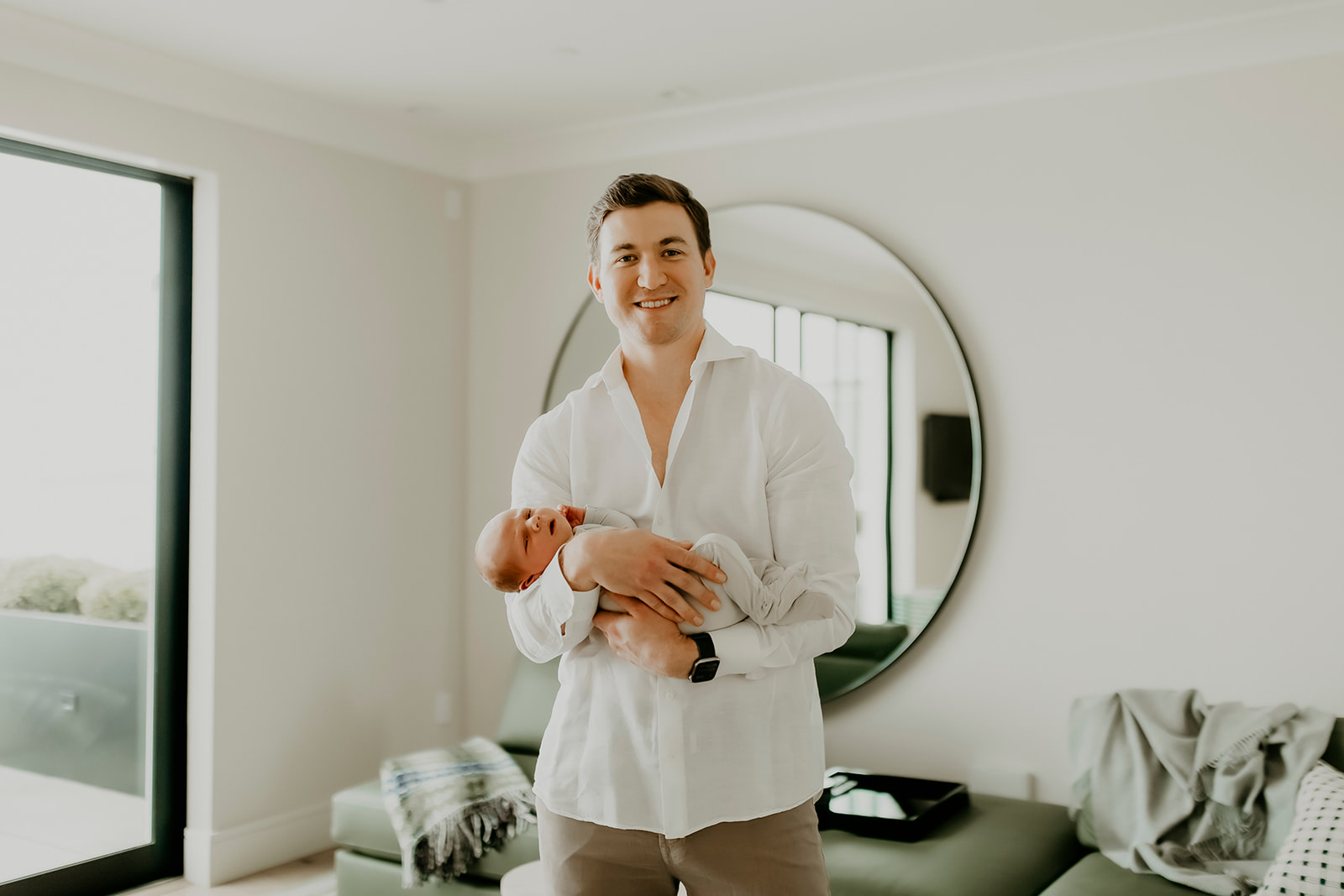 Shefali Parekh | Heartwarming In-Home Newborn Session: Maggie & Alex Black in Cow Hollow, San Francisco Man standing holding his newborn