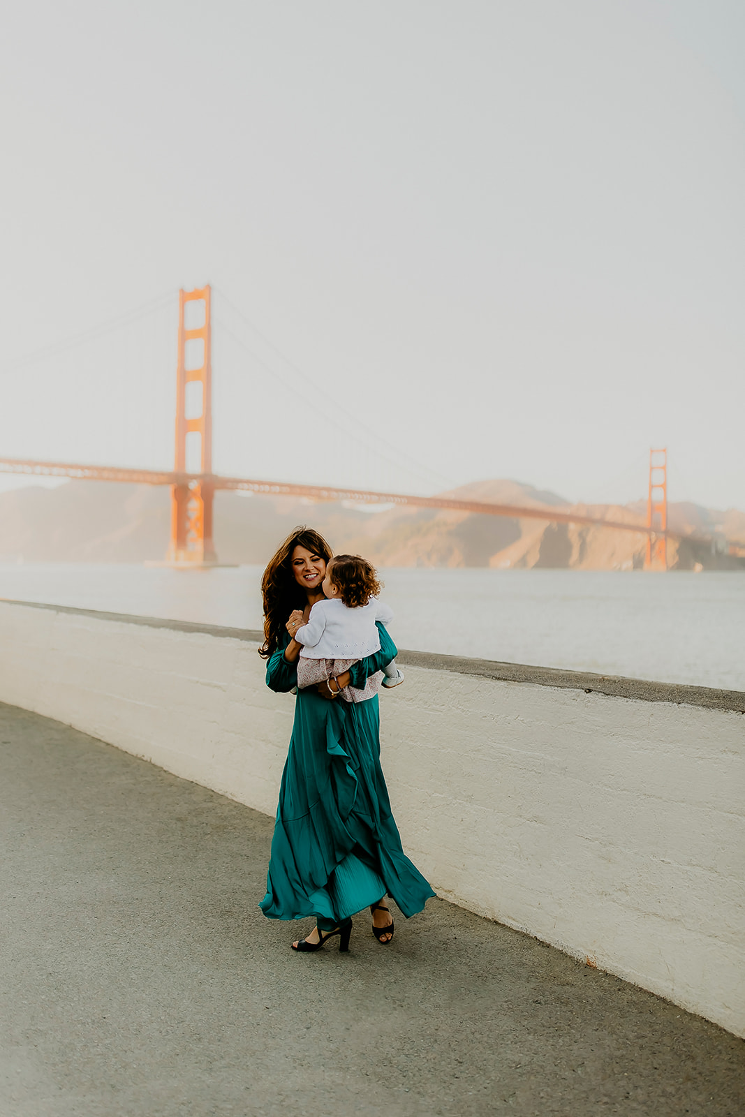 Shefali Parekh | The Best Location for Family Photography: Crissy Field Pamela Lastiri swinging her daughter at Crissy Field overlooking the Golden Gate Bridge