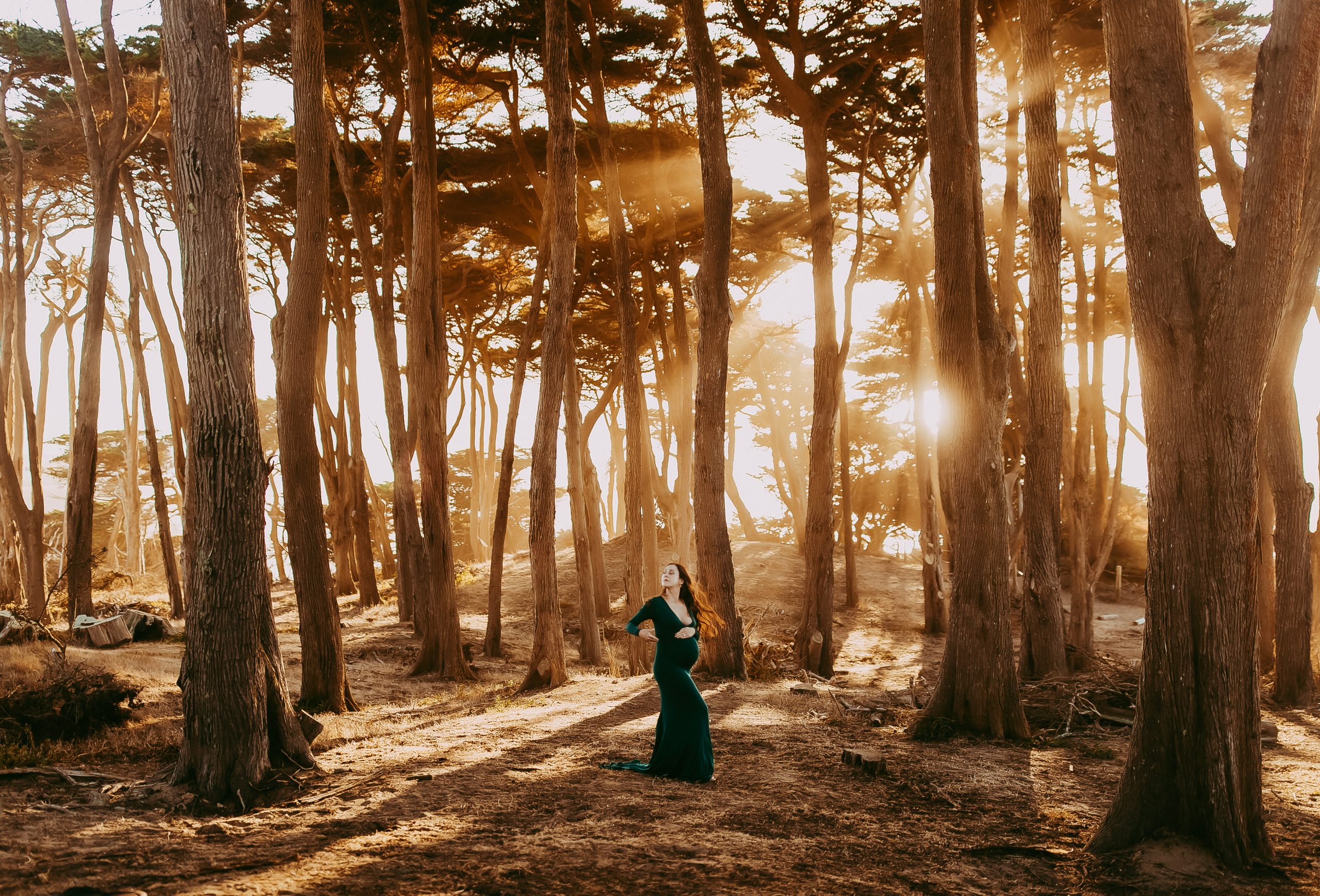 Stylish mom-to-be posing in a field with a warm sunset backdrop