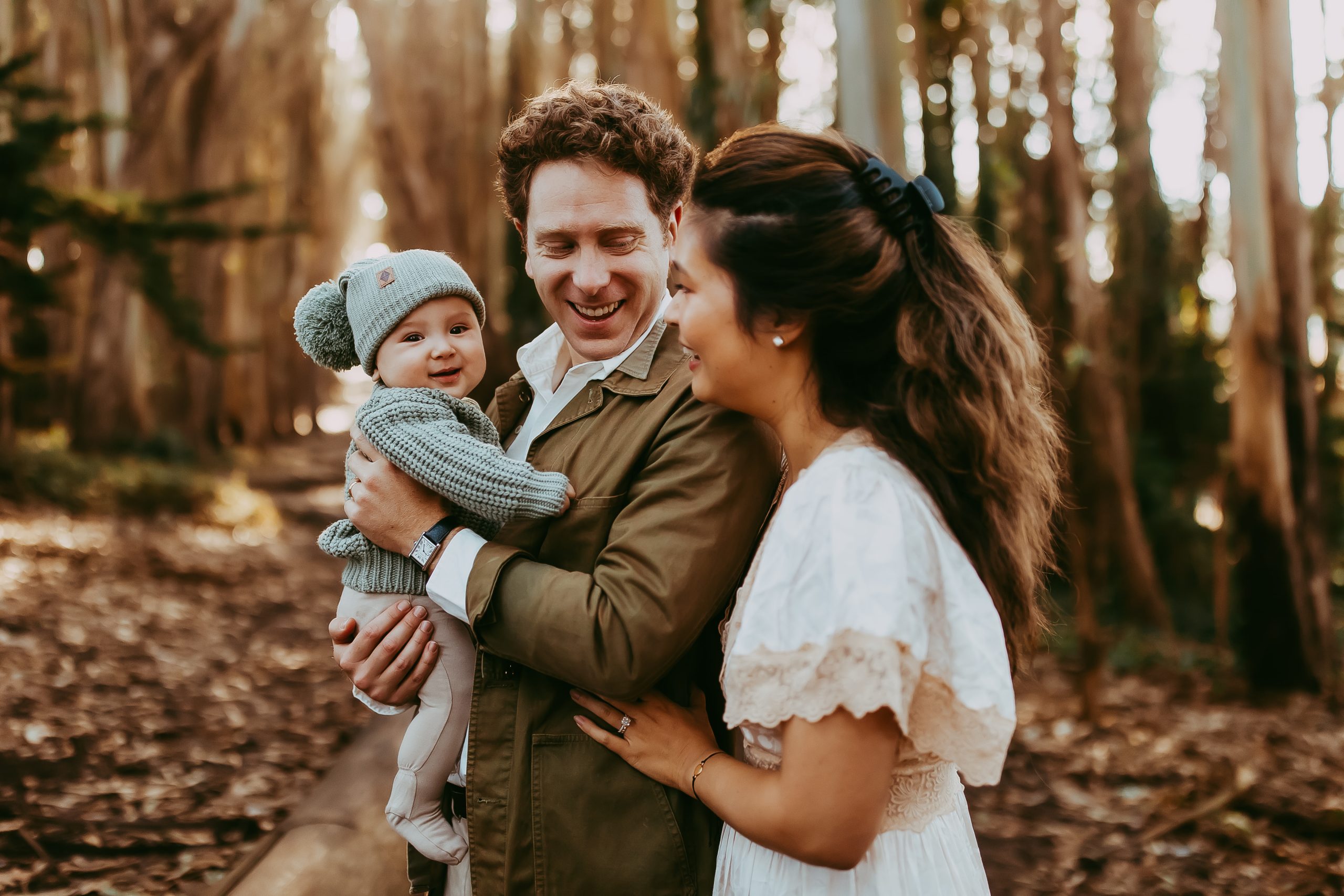 Shefali Parekh | Lovers Lane, San Francisco Family Photography Session Smiling baby boy in parents’ arms during a family shoot at Lovers Lane in the Presidio