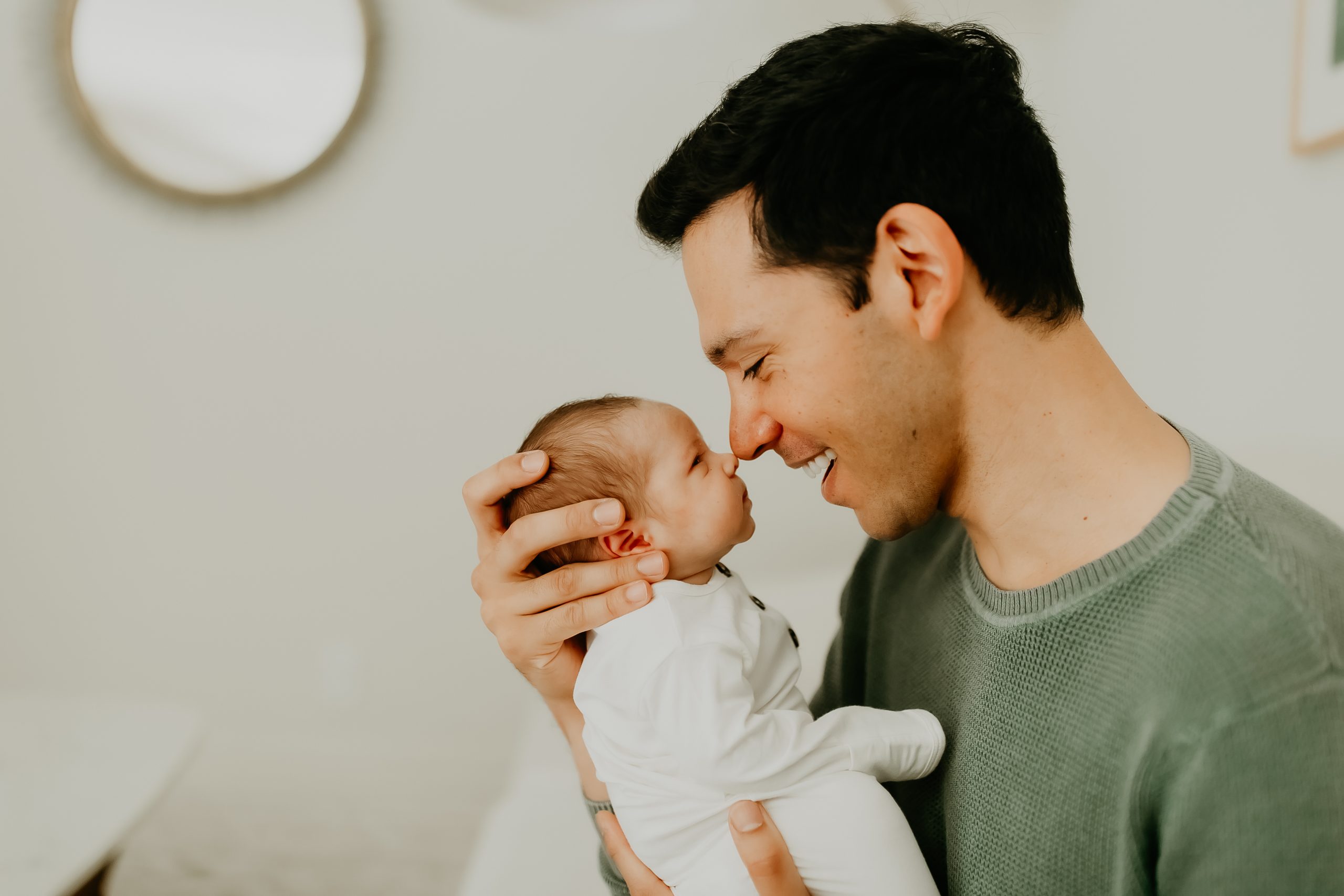 Shefali Parekh | Newborn Photographer Dad holding newborn in natural light at home