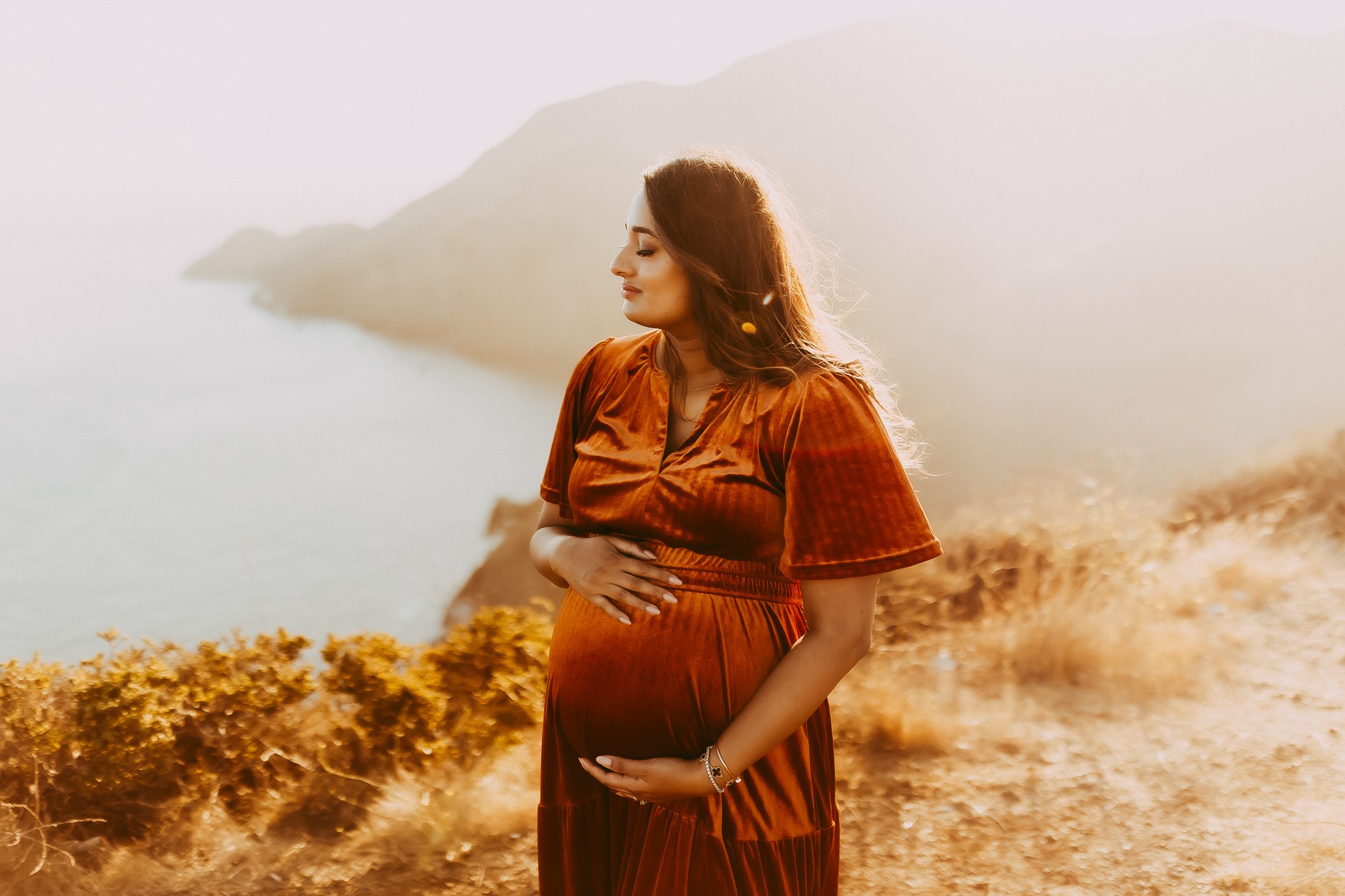 Shefali Parekh | Picnic Gender Reveal | Marin County Maternity Photographer Pregnant woman holding belly during unique outdoor maternity picnic session overlooking Golden Gate Bridge